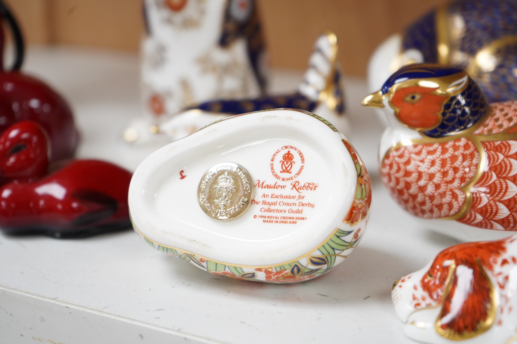 A collection of Royal Crown Derby Imari pattern paperweights, to include penguin and badger, together with three Doulton flambé animals, largest 19cm wide